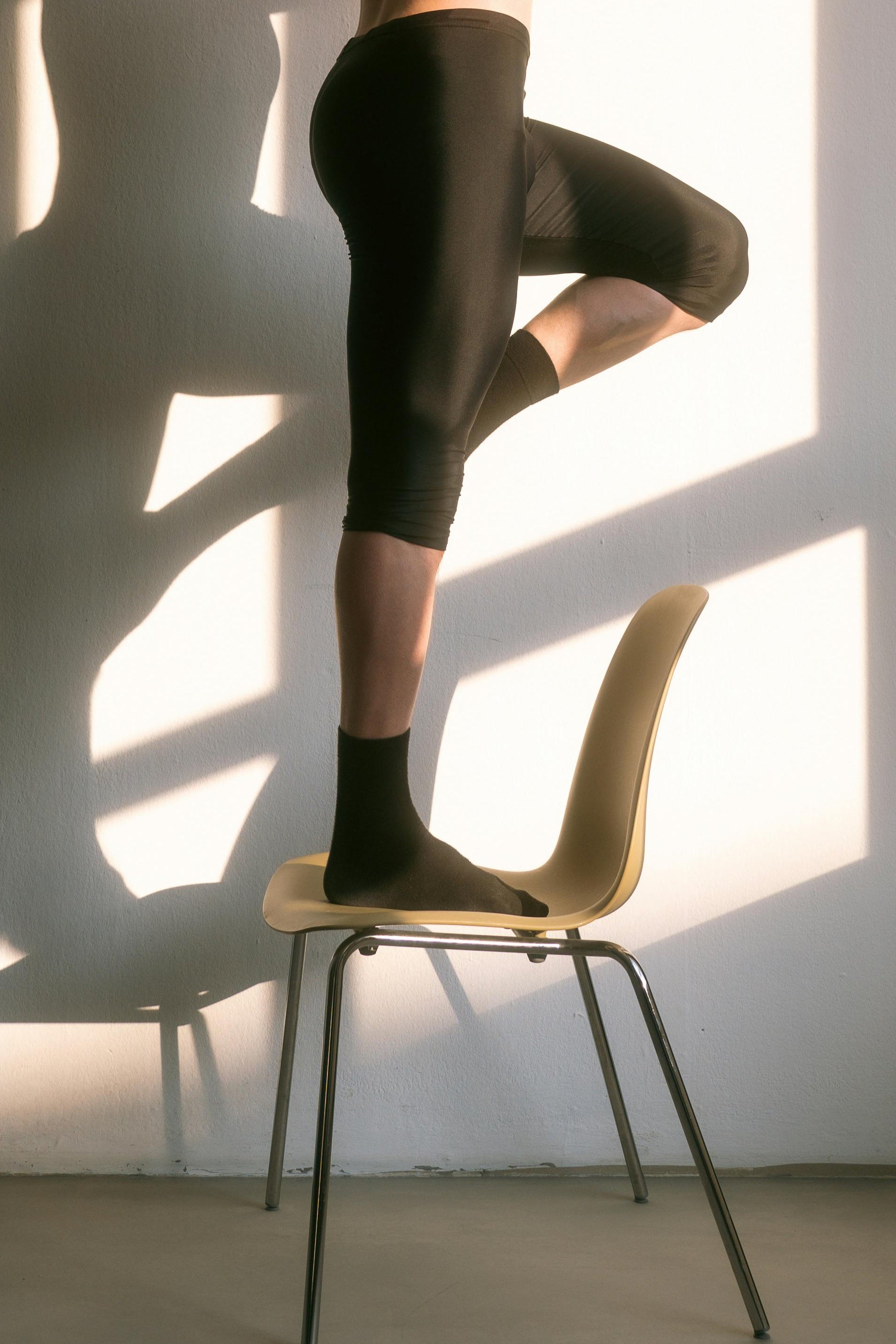 Man practicing pilates on a chair with sunlight streaming through a window